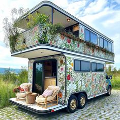 a bus that is sitting in the grass with flowers painted on it's side