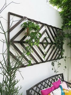 a bench sitting next to a wall with plants growing on top of it and an iron trellis behind it