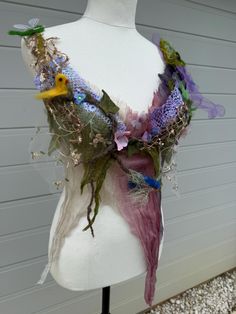 a white mannequin wearing a purple scarf with flowers and birds on it's back