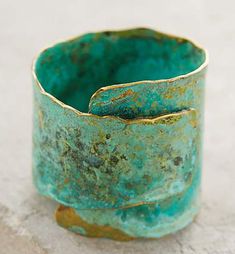 a green ring sitting on top of a stone slab next to a cement block with rusted edges