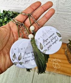 three wedding keychains in the palm of someone's hand with flowers on them