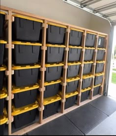 several bins are lined up against the wall in a storage area with yellow handles