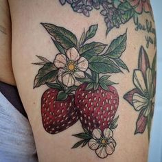 a close up of a tattoo with flowers and two strawberries