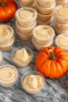 pumpkins and cream cheese in small plastic containers on a marble table with other food items