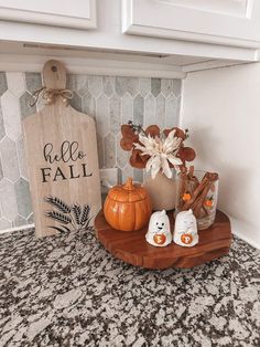 some pumpkins are sitting on a wooden tray in front of a sign that says hello fall