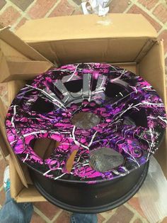 a purple and black cake in a box on the ground with other items around it