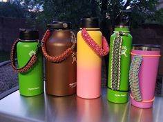 four different colored water bottles sitting on top of a metal table next to each other