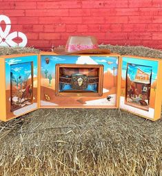 an old fashioned television sitting in hay next to a red brick wall