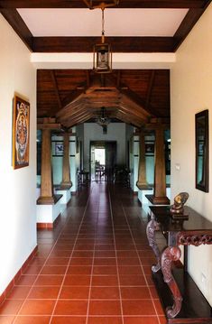 a long hallway with red tile floors and wooden ceiling beams on either side of the room