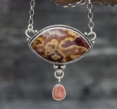 This necklace has a beautiful laguna agate with some beautiful patterning and a nice touch of druzy inside it. I have paired it with a guava quartz, the pink in the quartz was the perfect compliment to the tones in the agate. It's 2 inches wide and 2 inches long, a nice big statement piece! ♦Chain: This comes on a diamond ink chain that is currently 18-20 inches long, if you would like a different length just let me know. ♦Closure: lobster claw ♦ Metal: Sterling silver and fine silver Teardrop Agate Necklace With Large Stone, Ocean Jasper Gemstone Pendant Necklace, Agate Pendant Necklace With Large Stone, Teardrop Agate Gemstone Necklaces, Agate Teardrop Gemstone Necklace, Teardrop Agate Gemstone Necklace, Agate Necklace With Gemstone Accents For Gift, Agate Necklace With Gemstone Accents As A Gift, Agate Necklaces With Gemstone Accents For Gift