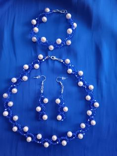 a necklace and earring set with white pearls on a blue satin background for an elegant look