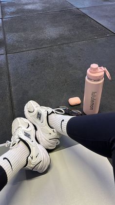 a pair of white sneakers sitting on top of a table next to a water bottle