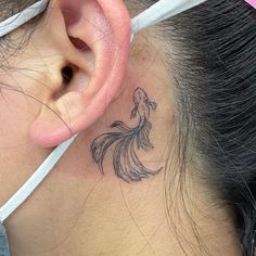 a woman with a tattoo on her neck behind the ear