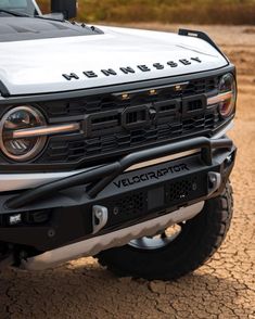 the front end of a white truck with black lettering on it's bumpers