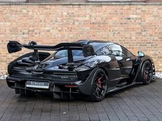 a black sports car parked in front of a brick wall