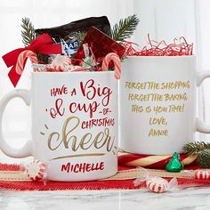 two coffee mugs filled with candy canes and candies on top of a table