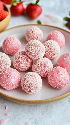 a plate filled with pink sprinkle covered donuts on top of a table