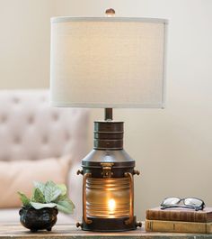 a table lamp with a white shade sitting on top of it next to a couch