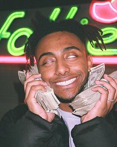 a man with dreadlocks talking on a cell phone while holding money in his hands