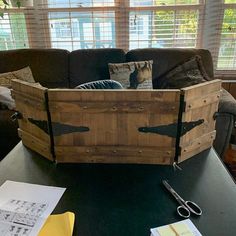 a wooden box sitting on top of a table next to a window with blinds in it