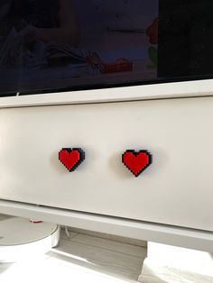 two heart shaped magnets are on the side of a white cabinet in front of a television