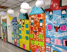 a hallway decorated with brightly colored paper houses and white pom - poms hanging from the ceiling