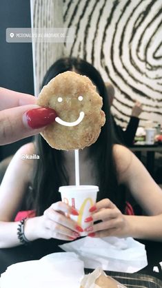 a person holding a doughnut with a smiley face on it's stick in their hand