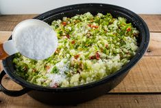 a large pot filled with food on top of a wooden table next to a spoon