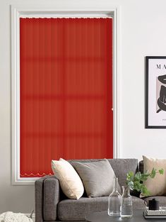 a living room with a couch, coffee table and red vertical blinds in the window