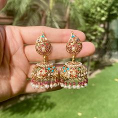 Featuring a medium sized jadau jhumka in 22k gold studded with navratna colours. The elegant design provides a sophisticated yet timeless look, perfect for adding a touch of glamour to your look. Elegant Meenakari Gold Plated Jhumkas, Elegant Multicolor Cutdana Jhumkas, Gold-plated Meenakari Jhumkas In Dangle Style, Festive Meenakari Gold-plated Jhumkas, Jadau Jhumka, Luxury Ruby Meenakari Jhumkas, Gold Indian Jewelry, 22k Gold Jewelry Necklaces, 22k Gold Jewelry