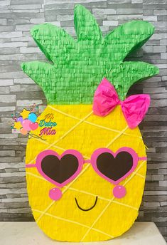 a pineapple made out of construction paper with pink heart glasses and a bow on top