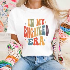 The price is per shirt Celebrate your LOVE and PRIDE with our beautiful retro-style Rainbow Engayged shirts!  - Shirt Details:  * 100% ring-spun cotton * Sport Grey is 90% ring-spun cotton, 10% polyester * Dark Heather is 65% polyester, 35% cotton * 4.5 oz/y² (153 g/m²) * Pre-shrunk * Shoulder-to-shoulder taping * Quarter-turned to avoid crease down the center This is a unisex shirt.  Unisex is a traditional fitted men's t-shirt size, but they look great on both men and women. * Men should order Retro White Tops For Anniversary, Vintage White T-shirt As Gift, Engagement Tshirt, Lesbian Proposal, Lgbt Wedding Attire, Vintage Pride, Lesbian Engagement Photos, Queer Tshirts, Lgbtq Wedding Invitation