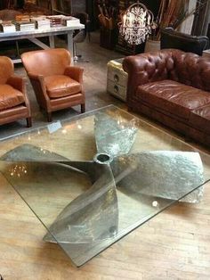 a living room with leather couches and glass coffee table in it's center