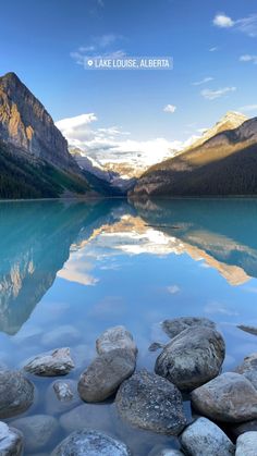 a lake surrounded by rocks and mountains under a blue sky with the words lake louise, alberta