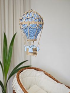 a blue hot air balloon hanging from the ceiling next to a potted plant in a wicker basket