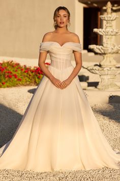 a woman in a wedding dress posing for the camera with her hands on her hips