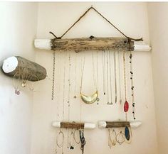 a wall hanging made out of driftwood and various necklaces attached to the wall