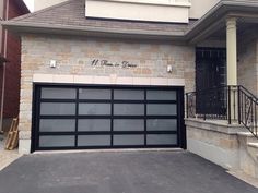 a black garage door is open in front of a brick building with stairs leading up to it