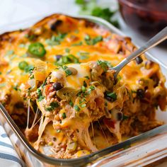 a casserole dish with meat, vegetables and cheese being lifted from the casserole