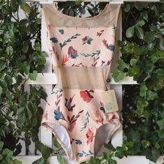 a women's bodysuit with floral print on the front and back, hanging from a wall