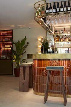 a bar with wine glasses hanging from the ceiling and stools in front of it