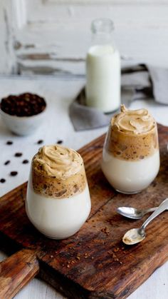 two desserts are sitting on a cutting board next to a glass of milk and spoon