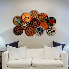 a white couch sitting in front of a wall mounted with colorful plates on it's side