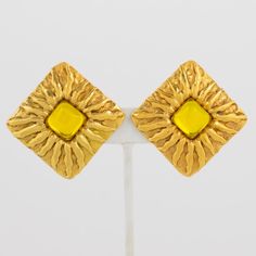 This is part of Chairish’s Costume Jewelry assortment.  These lovely Jean Patou Paris signed clip-on earrings feature a gilt metal square shape with a carved sun pattern and are embellished with a bright yellow Gripoix poured glass cabochon in the center. Each piece is signed with a tag underside reading Jean Patou - Paris. Measurements: 1.75 in wide (4.5 cm) x 1.75 in high (4.5 cm).  Please see the measurements noted above in the description for the best approximate dimensions. Formal Yellow Clip-on Earrings, Luxury Gold Cabochon Clip-on Earrings, Luxury Yellow Clip-on Earrings, Vintage Yellow Gold Metal Clip-on Earrings, Vintage Yellow Gold Cabochon Clip-on Earrings, Sun Pattern, Jean Patou, Accessories Jewelry Earrings, Clip Earrings