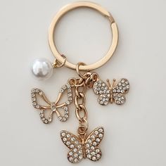 a key chain with two butterflies and a pearl