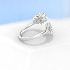 a three stone diamond ring on a white surface with light blue back droping in the background