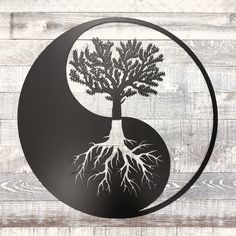 the yin symbol has a tree with roots growing out of it in front of a wooden wall