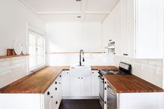 a kitchen with white cabinets and wood counter tops, along with a stove top oven