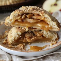 two pieces of apple pie stacked on top of each other in a white plate with caramel drizzle