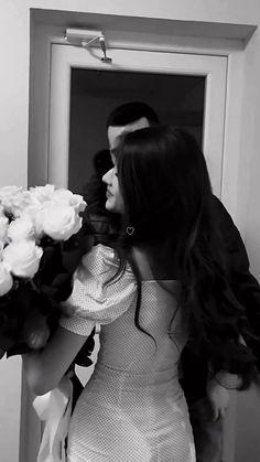 a man and woman standing in front of a door with flowers on their hands,